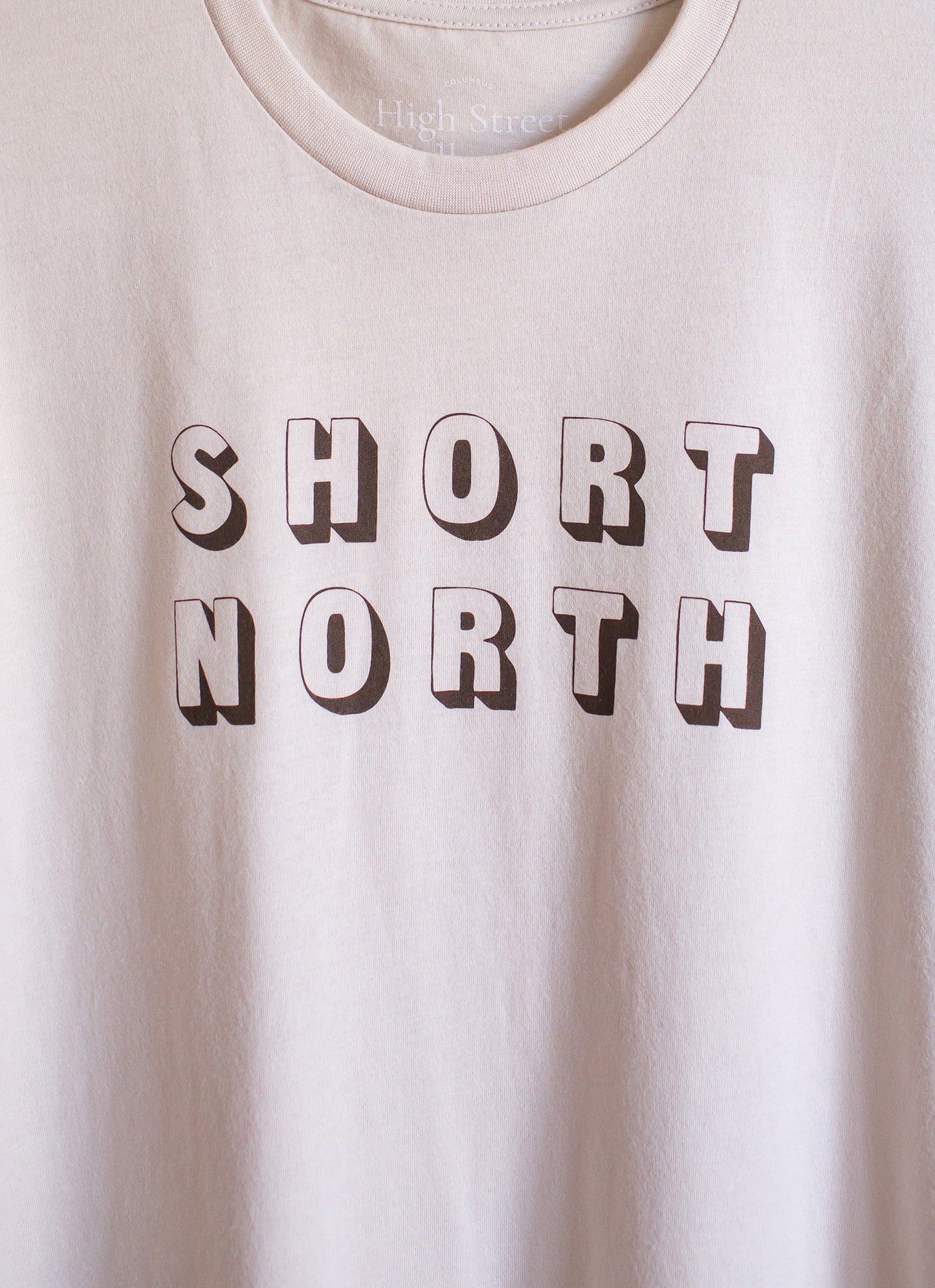Sand colored sueded crewneck tee with cocoa colored Short North graphic at front.