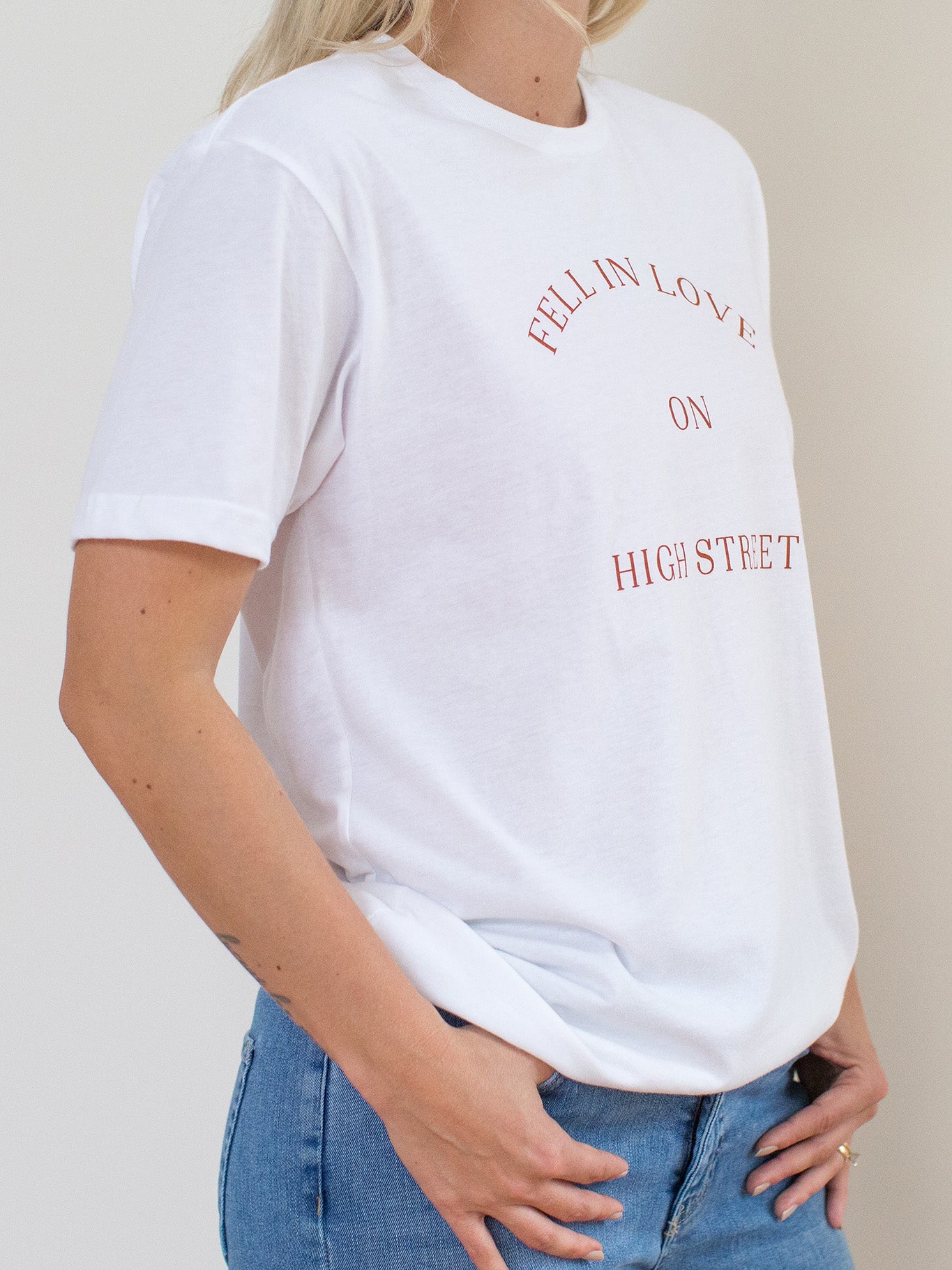 Model wearing white sueded tee with Fell In Love On High Street graphic at front