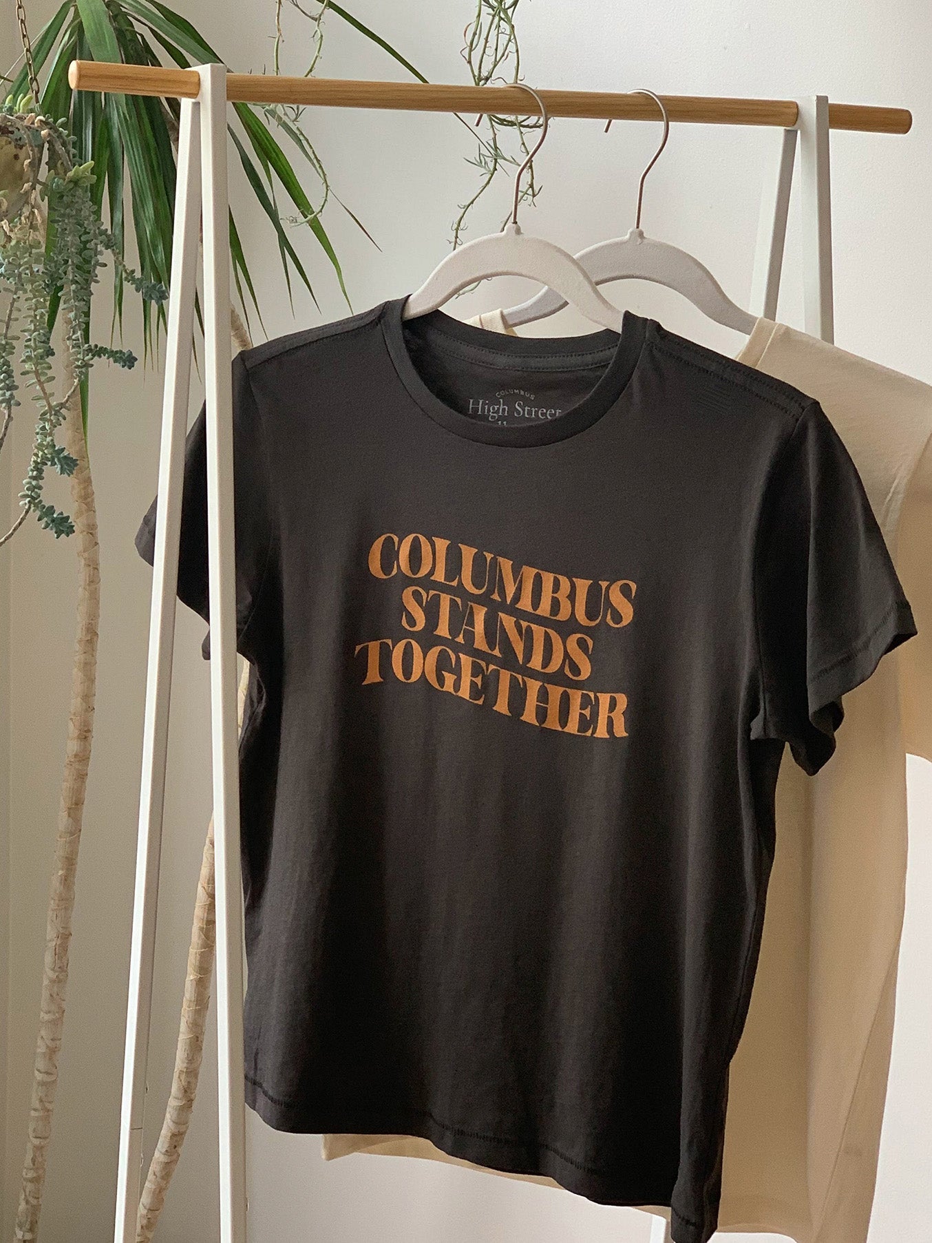 Cropped vintage black high-waisted tee with Columbus Stands Together tan graphic at front.
