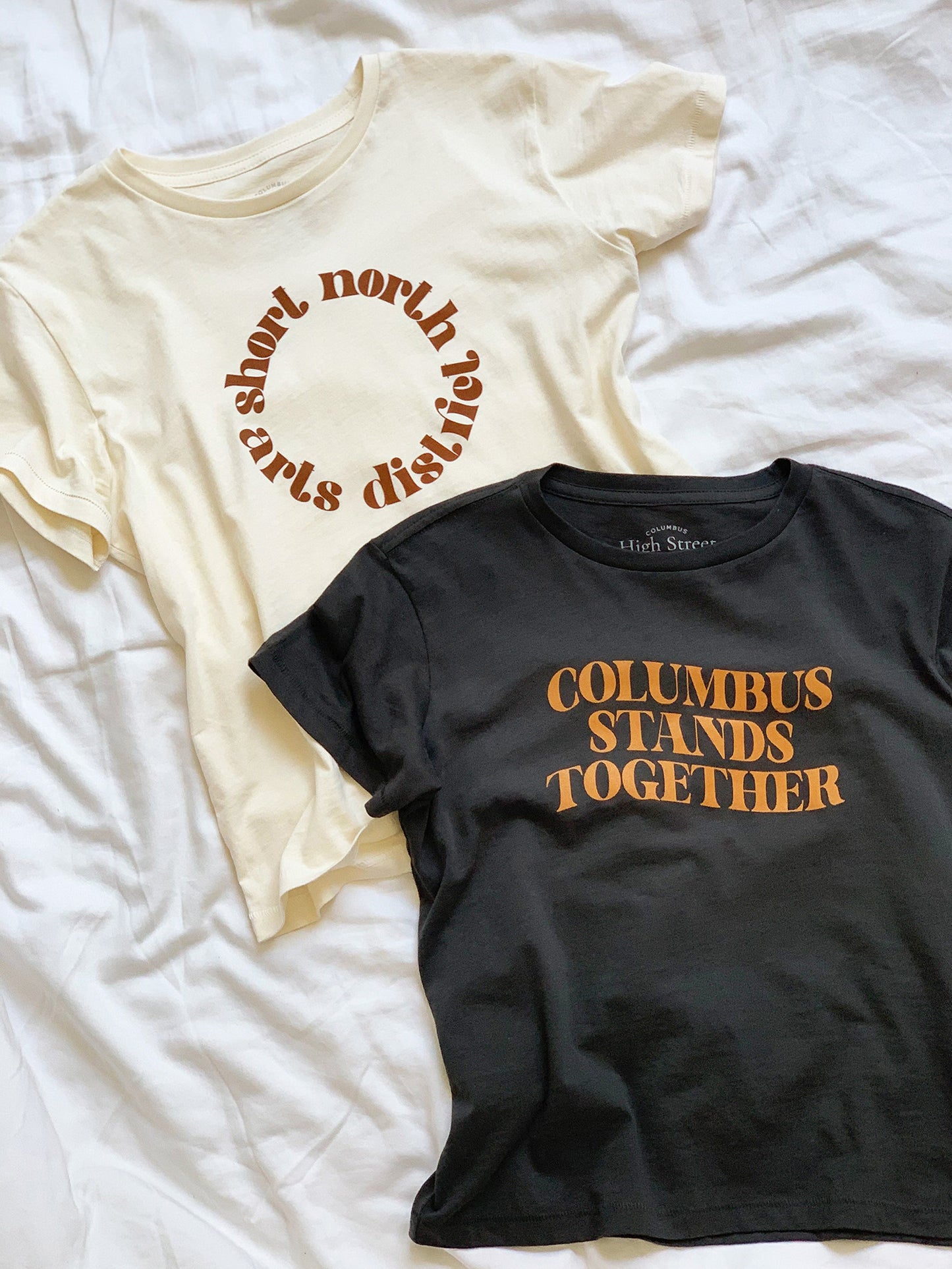 Cropped vintage black high-waisted tee with Columbus Stands Together tan graphic at front.
