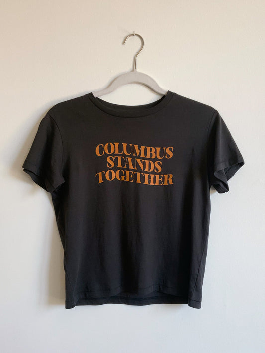Cropped vintage black high-waisted tee with Columbus Stands Together tan graphic at front.