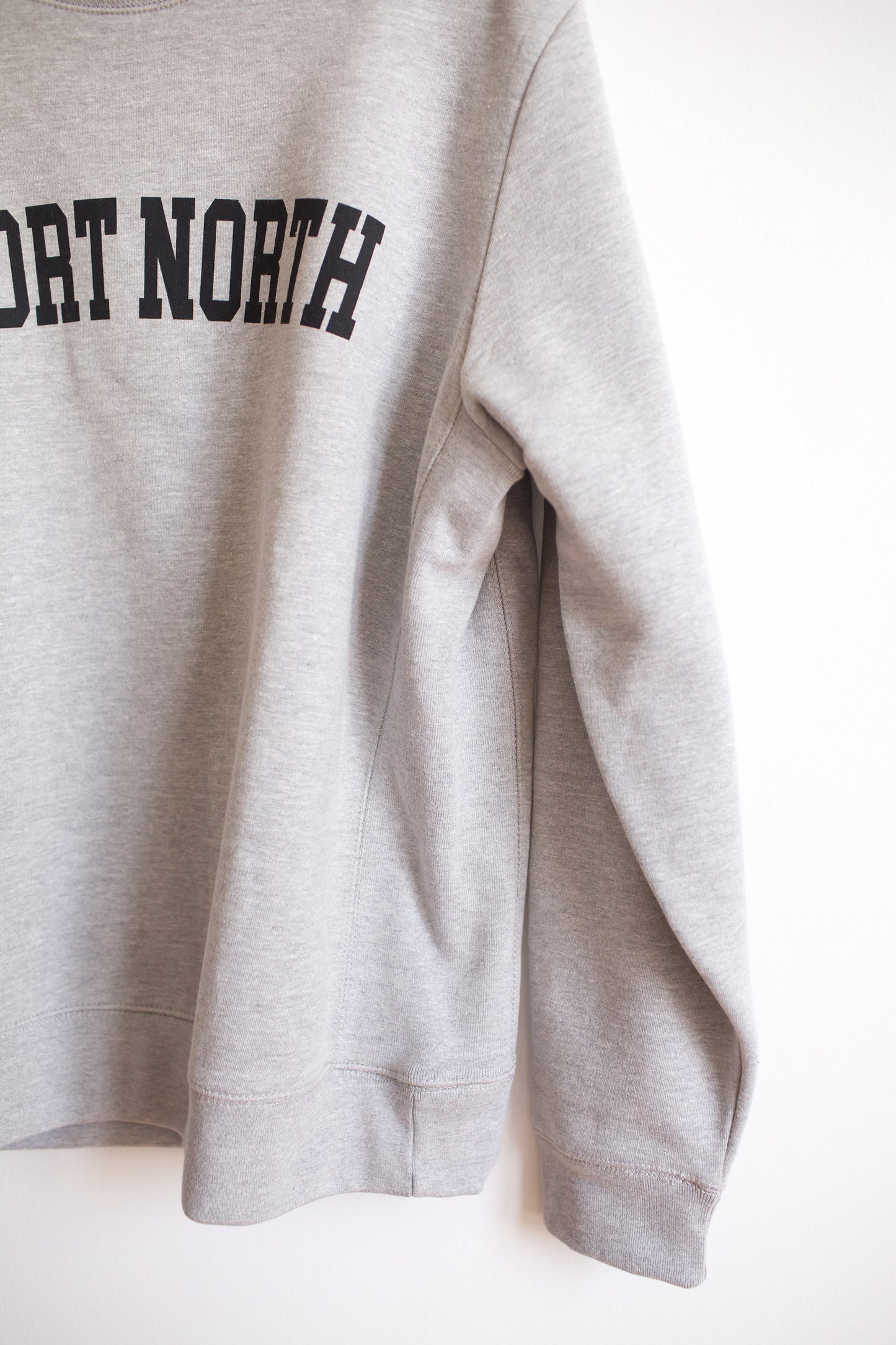 Ribbed side detail of heather grey crewneck sweatshirt with Short North graphic at front.