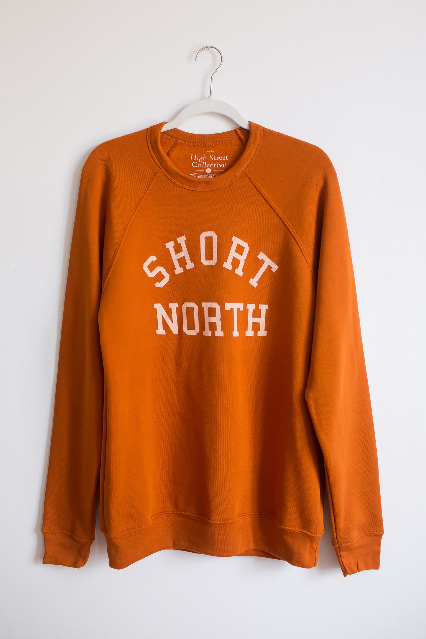 Rust colored slim fit, crewneck sweatshirt with Short North graphic at front. This style has raglan sleeves for a vintage look.