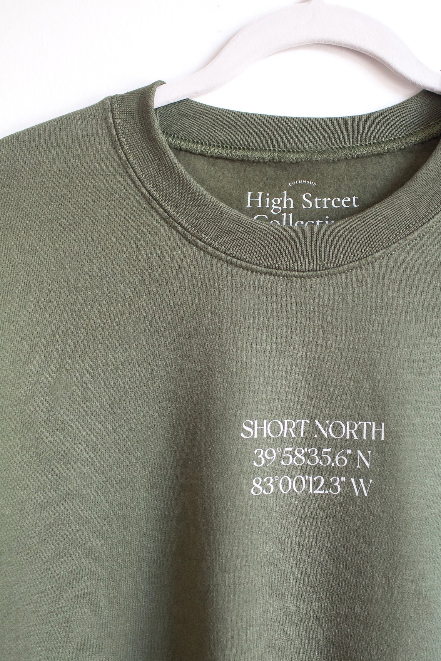 Military green crewneck sweatshirt with Short North coordinates graphic at front.