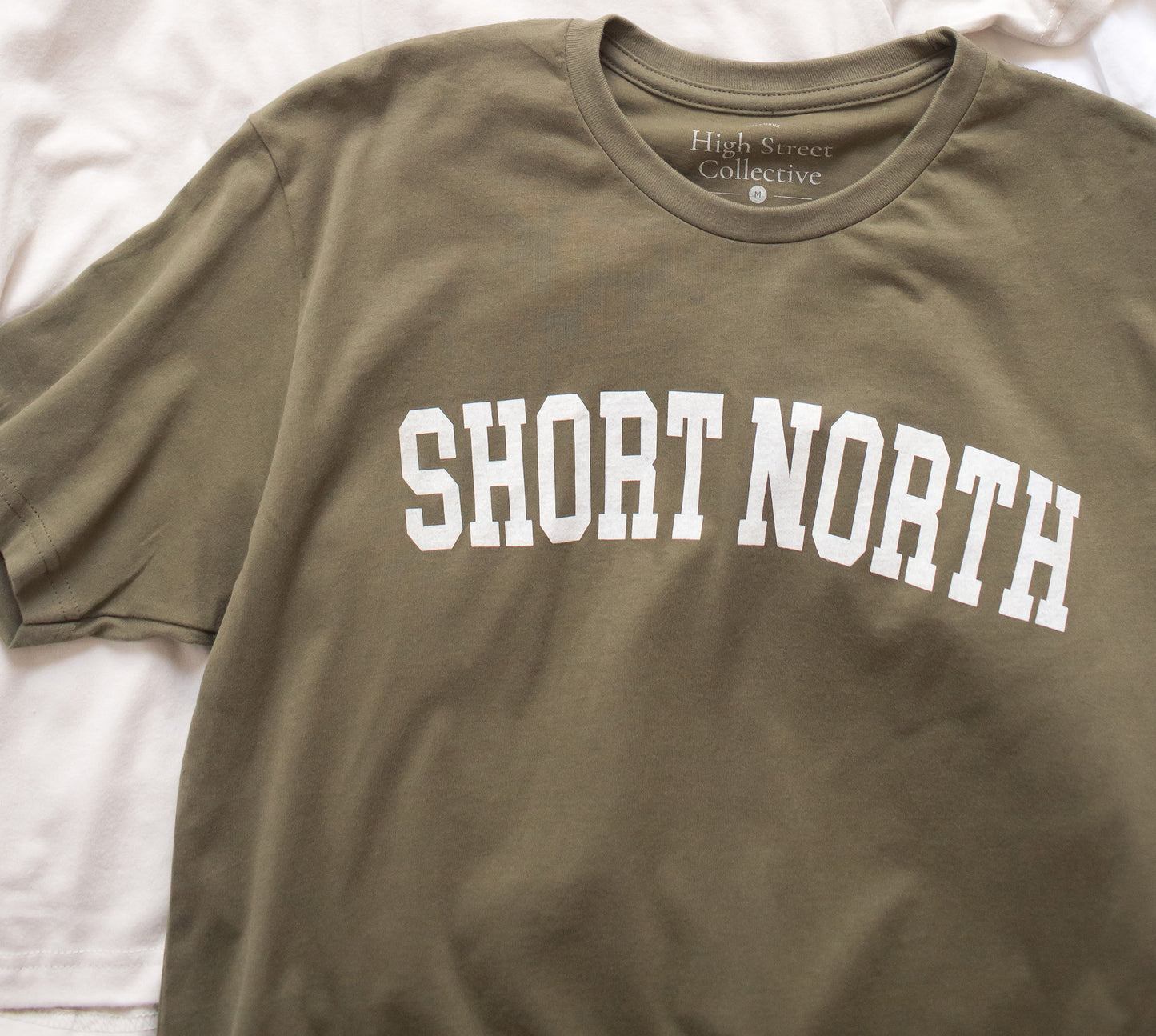 Dusty green sueded tee with white Short North graphic at front.