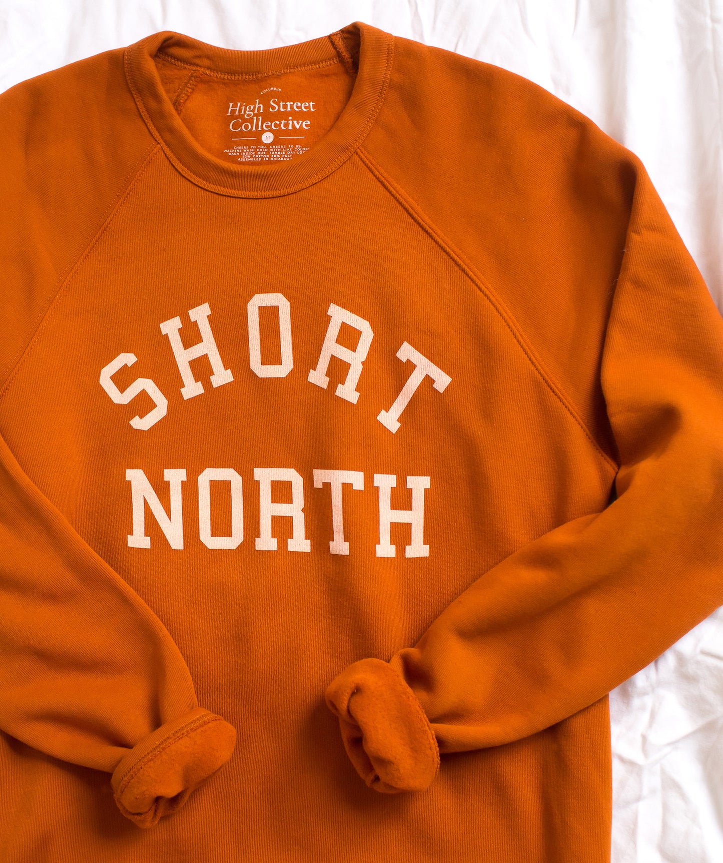 Rust colored slim fit, crewneck sweatshirt with Short North graphic at front. This style has raglan sleeves for a vintage look.
