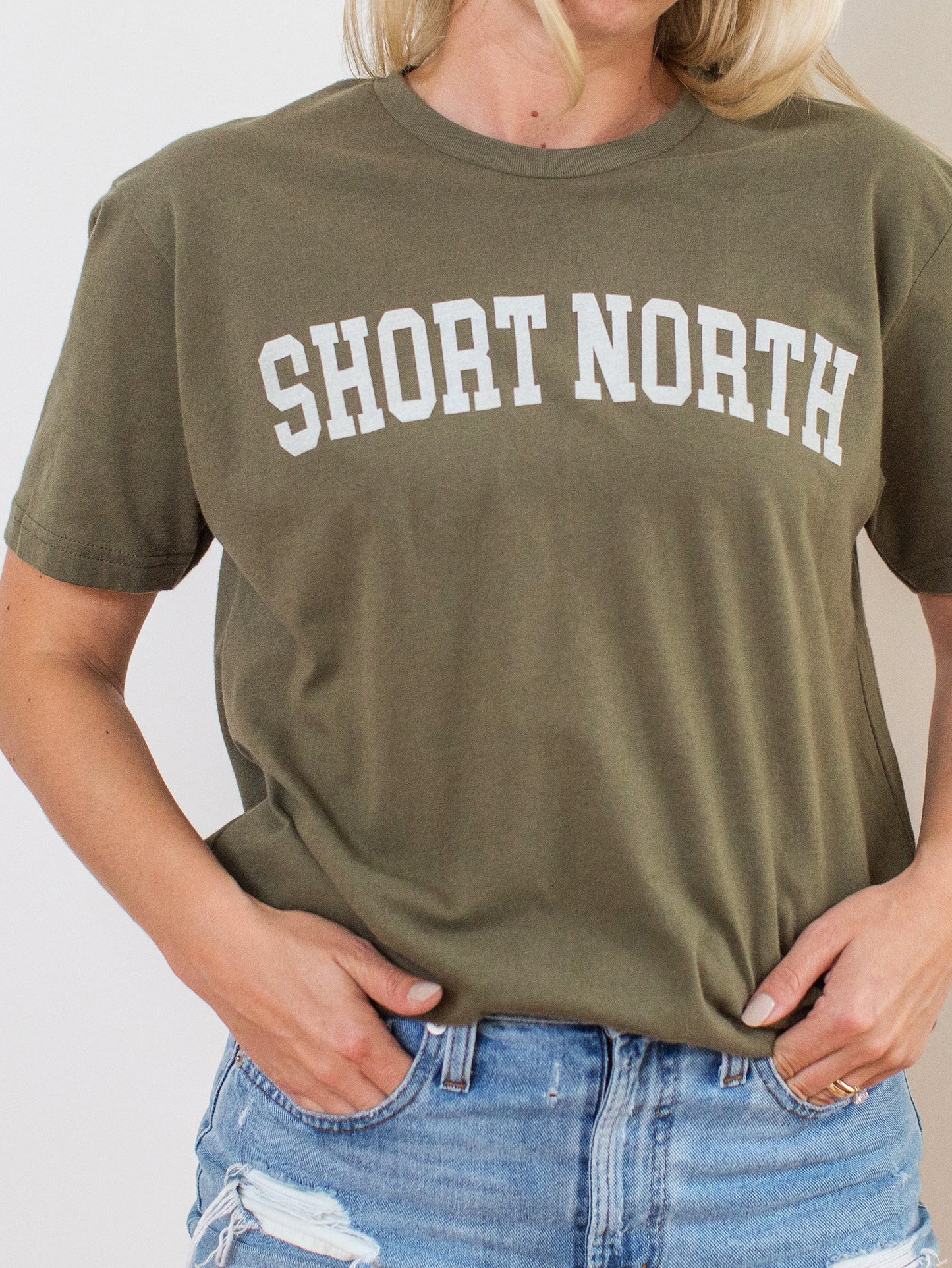 Model wearing dusty green sueded crewneck tee with white Short North Columbus, Ohio graphic at front