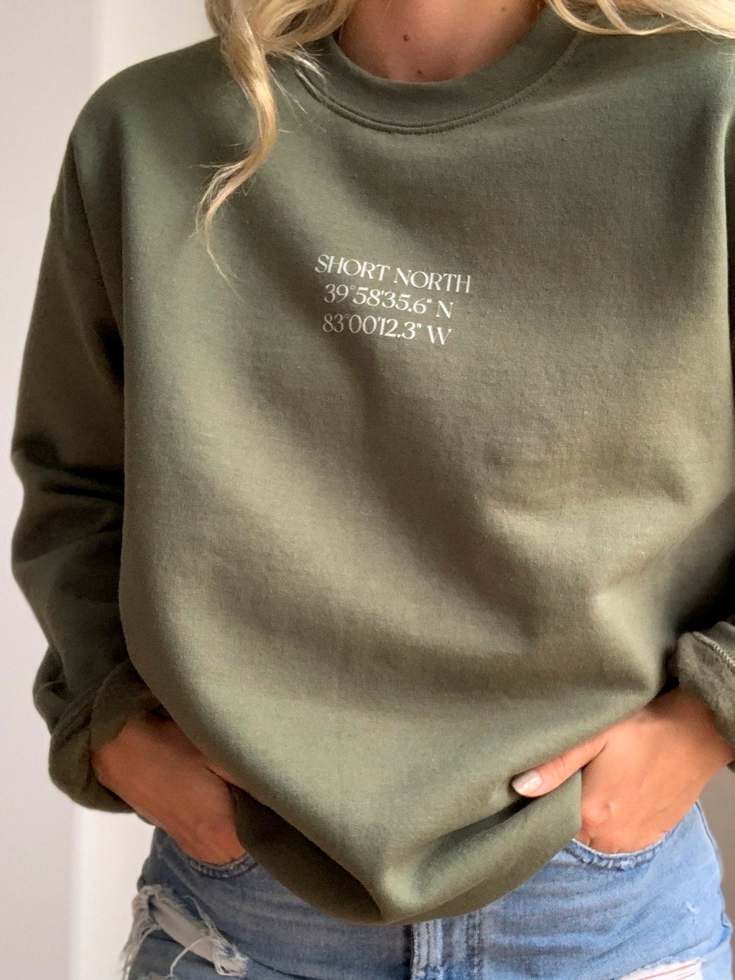 Model wearing military green crewneck sweatshirt with Short North Columbus, Ohio graphic at front