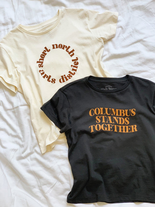 High-Waisted cream tee with Short North Arts District Columbus, Ohio circular graphic on front and vintage black cropped tee with Columbus Stands Together graphic at front